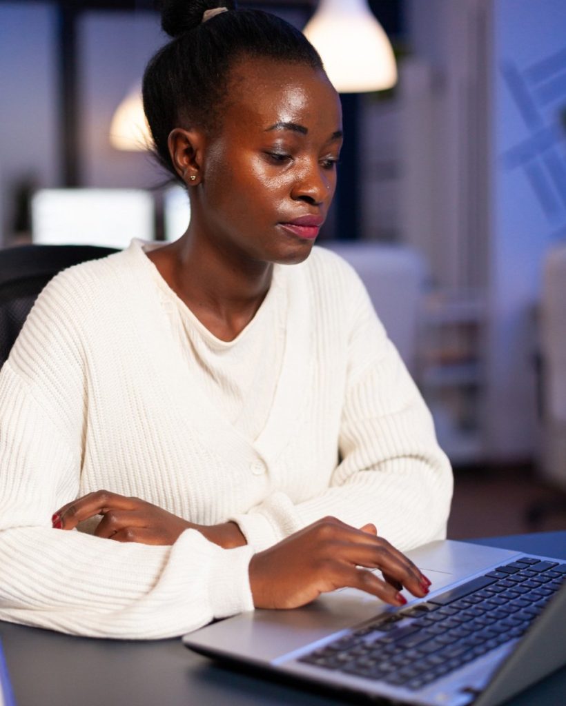stressed-african-manager-woman-working-with-financial-graphs-checking-statistics-typing-on-laptop-reading-raports-late-at-night-in-start-up-office-doing-overtime-to-respect-deadline-of-project